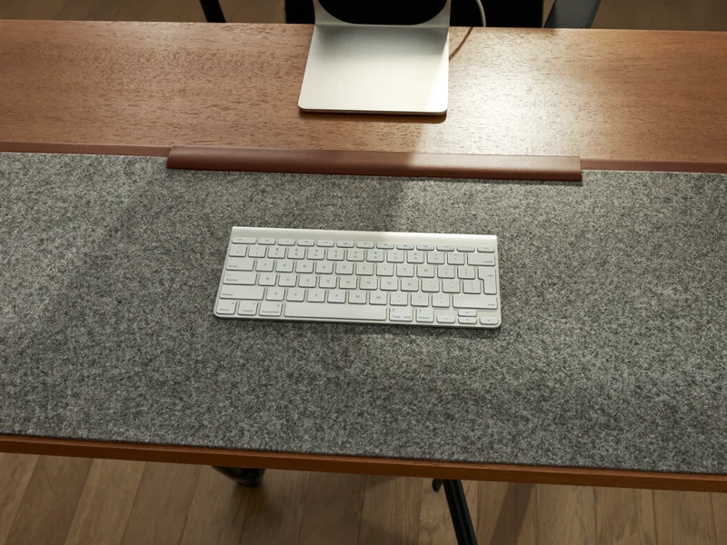 Schreibunterlage aus grauem Filz und braunem Kunstleder unter einer Tastatur
