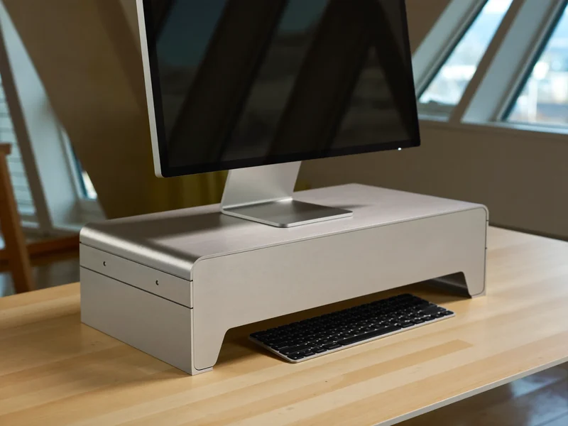 Monitorerhöhung aus gebürstetem Aluminium mit darunter geschobener Tastatur